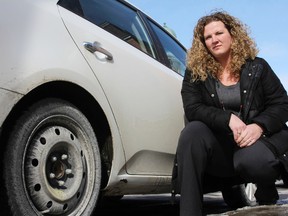 Alynn Boyle kneels next to the car she says was damaged by a pothole on a downtown street. Boyle says she is frustrated the city will not compensate her for the $800 in damage the vehicle sustained.
Elliot Ferguson The Whig-Standard