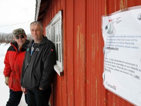 Long-time commercial fishermen Tim McCormack, right, and John Rorabeck stand along an eviction sign that was put up on one of McCormack's fishing sheds at Prince Edward Point National Wildlife Area, south of Milford, Ont. � informing commercial fishermen at the harbour their personal property will be demolished March 4, 2013. (Friday, Feb. 22, 2013). JEROME LESSARD/The Intelligencer/QMI Agency