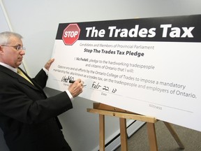 Nipissing MPP Vic Fedeli signs a Stop the Trades Tax pledge Friday during a news conference at his Main Street office.