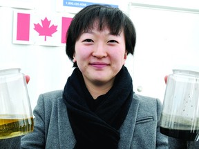 Luann Fu, the lead researcher in a Queen's University pilot project at the Brockville sewage plant, illustrates the difference between sludge, at right, and the liquid that emerges once it goes through a Newterra membrane being tested at the facility (RON ZAJAC/The Recorder and Times).