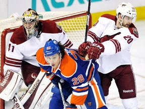 Edmonton Oilers' Ryan Jones (28) of Chatham is checked by Phoenix Coyotes goalie Mike Smith and Chris Summers on Saturday in Edmonton. (DAN RIEDLHUBER/Reuters)