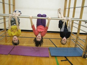 Hanging upside down from a bar are, from left, Grade  4 students, Thomas Wilson, Kaedence Corke, and Corbyn Hansen.