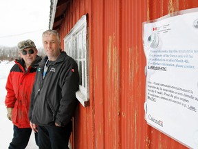 Longtime commercial fishermen Tim McCormack, right, and John Rorabeck stand along an eviction sign that was put up on one of McCormack’s fishing sheds at Prince Edward Point National Wildlife Area, south of Milford. (JEROME LESSARD QMI file photo)