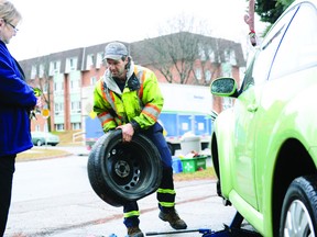 Don Myers, of A&R Towing, removes a flat tire from Gerda Giddings's Christmas-decorated Volkswagen on Kensington Parkway Monday morning. FILE PHOTO