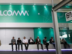People sit next a Qualcomm stand at the Mobile World Congress at Barcelona, Feb. 27, 2013. REUTERS/Albert Gea