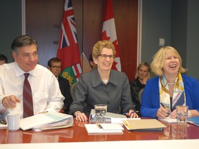 Premier Kathleen Wynne is flanked by Finance Minister Charles Sousa and Health Minister Deb Matthews as the provincial cabinet meeting opens in Sault Ste. Marie.
