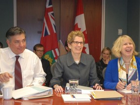 Premier Kathleen Wynne is flanked by Finance Minister Charles Sousa and Health Minister Deb Matthews as the provincial cabinet meeting opens in Sault Ste. Marie.