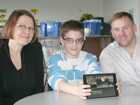 Colin Price, a 13-year-old student in Grade 8 at Queen Elizabeth II Public School, shows off one of the 40 iPad minis that were donated to the school in memory of Dave Allin. With Colin are Dave's wife, Helen, and Carson Warrener. The Warrener family, which owns the Downtown Chatham Centre, along with mall retailers and staff, donated $20,000 for the iPad mini lab.