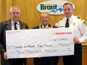 Ken Hall, left, senior advisor of community relations for Enbridge, presents County of Brant Mayor Ron Eddy and Fire Chief Paul Boissoneault with a cheque for $10,000 to purchase new safety equipment critical to the personal protection of firefighters and first responders. SUBMITTED PHOTO