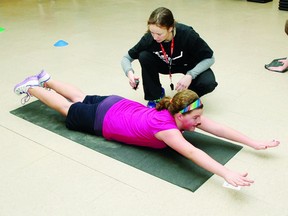 Lesley Peplinskie, Grade 6/7 teacher at St. Francis of Assisi School, looks on as Grade 6 student Rheanna Phillips does a locust pose during a boot camp session at the Petawawa Civic Centre recently.