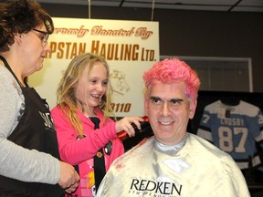 Chloe Cudmore, 11, helps volunteer stylist Brenda Pickard shave grandfather and Grande Prairie Fire Department Fire Chief Dan Lemieux’s head at the Reed Energy Group Curl for Cancer fundraiser Saturday. The event raised a total of $85,000 to help local cancer patients get through the financial burden of their treatment. (Elizabeth McSheffrey/Daily Herald-Tribune)