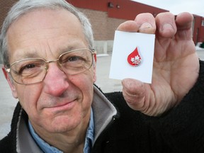 Andy Galea holds up his 250th blood donation pin.