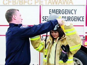 Firefighter Trevor McNichol of the CFB Petawawa Fire Department helps Brianna Amikons, 13, of the Algonquins of Pikwakanagan First Nation,  adjust her helmet during a visit to the fire hall by Aboriginal youth during a weekend gathering organized by the Ontario Provincial Police East Region Provincial Liaison Team.