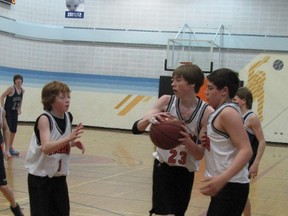 Mayerthorpe Junior Senior High School junior Tigers, from left,  Terin Roberts, Jesse Lasher, and Keith Stensrud, cluster around the ball in a game against the St. Joseph High School.