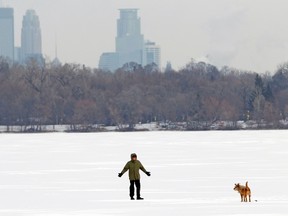A man walks his dog across Lake Harriet near Minneapolis  January 23, 2013. (REUTERS FILE/Eric Miller)