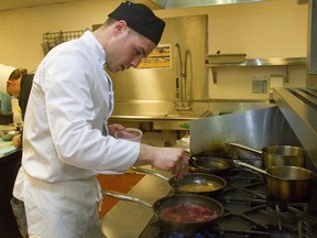 Fanshawe culinary student Terrance Copeland checks on his simmering dish while roasting red peppers as he competes in Fanshawe College?s Iron Chef competition at the school. Eight students were paired with eight local chefs from the Canadian Association of Foodservice Professionals to make a meal using a secret ingredient, which turned out to be Dead Elephant Ale from Railway City Brewery in St. Thomas. (MIKE HENSEN, The London Free Press)