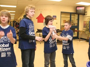 Jordi Murdoch, right, hands a bag of pennies to Jesse Guilderson at the 
head of the human chain at Meadowbrook Middle School on Friday.

CHRIS SIMNETT/AIRDRIE ECHO