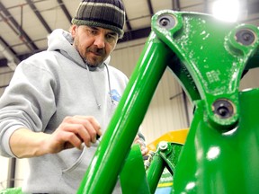 Brian Hebert of Prairie Coast Equipment carefully applies last-minute touch-up paint to a John Deere H-380 loader, Wednesday at the TEC Centre. Vendors were scurrying Wednesday putting the finishing touches on their displays before the Peace Country Classic Agri-Show begins today. (Adam Jackson/Daily Herald-Tribune)