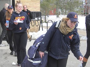 A loaded-down Katie Duncan carries some of her gear to the waiting bus, followed by Samantha Regier, as members of the Queen’s University women’s hockey team prepare for their trip to Toronto Wednesday for the Canadian Interuniversity Sport championship tournament. (Michael Lea/The Whig-Standard)