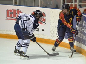 Jenna Pitts of the St. Francis Xavier X-Women and Brittany McHaffie of the Queen’s Golden Gaels keep their eyes on the puck during a game at the Canadian Interuniversity Sport women’s hockey championship tournament in Toronto on Friday. McHaffie scored the only goal for the Gaels, who lost 2-1 in overtime. (Jamie MacDonald/Canadian Interuniversity Sport)