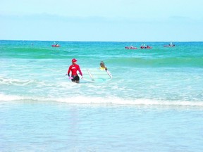 Surf Diva instructor Izzy Tihanyi leads Texas tourist Kelsea Russo through the surf at Southern California?s La Jolla beach. At right, Tihanyi instructs a novice group of boarders, including Londoner Barbara Taylor (far right), on the rigours of stand-up paddleboarding. (BARBARA TAYLOR QMI Agency)