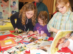 From left, Sarah Medel, Rebekah Medel, and Kelly Temoin of Tillsonburg look over a selection of free books during the annual Family Literacy Day event Thursday evening at Avondale United Church in Tillsonburg. KRISTINE JEAN/TILLSONBURG NEWS/QMI AGENCY