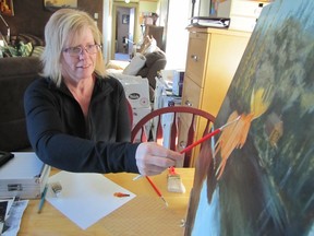 Sue Thompson works on a painting.