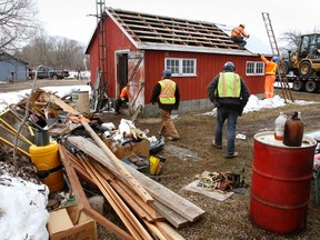 Workers with Leo Tessier, NAT-CAP Construction Inc. of Winchester, Ont. empty out and demolish fourth-generation commercial fisherman Tim McCormack's fishing buildings (two) at Point Traverse harbour in Prince Edward Point Wildlife Area at Monday. (JEROME LESSARD/QMI Agency)