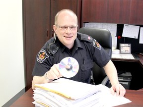 Chatham-Kent police Const. George Sanderson holds a CD above a stack of court briefs at the Chatham, Ontario courthouse Monday March 11, 2013. The Chatham-Kent Police Service is using new technology to capture efficientcies and move away from paper records. VICKI GOUGH/ THE CHATHAM DAILY NEWS/ QMI AGENCY