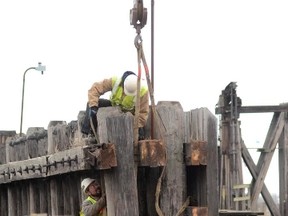 Tom Morgan and Rich Killian strap pilings to ta crane Tuesday morning as a crew worked to remove the bumper on the old ferry dock south of the Maritime center in Port Huron, Mich. Crews hope to be finished with the demolition by the middle of next week. (WENDY TORELLO/ TIMES HERALD)