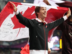 High jumper Derek Drouin of Corunna hoists the Canadian flag while celebrating his bronze medal at the London Olympics this past summer. Drouin set a Canadian indoor record in the high jump this weekend at the NCAA Championships, clearing 2.35m to win the title. (PHOTO COURTESY OF ATHLETICS CANADA)