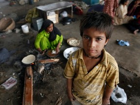 A Hindu boy stands near his mother and family who are living under a bridge in Karachi, Pakistan January 10, 2013. (REUTERS/Athar Hussain)