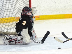 Quinte West Calderwood Automation Novice Hawks' Dawson Douglas tries to get a shot off on Napanee Stars' goalie Ryan Aldridge as heís being tackled by Stars' captain Owen Gibson during the Hawks' dramatic 3-2 overtime win Sunday at the Community Gardens.