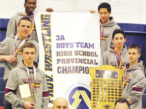 The Sabres wrestling team poses with their championship banner after a successful weekend at the provincial tournament.