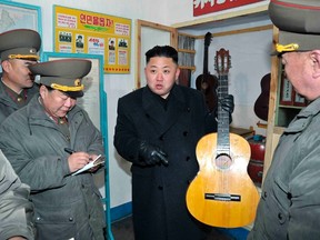 North Korean leader Kim Jong-Un (C) holds a guitar during his visit to a military unit on the Wolnae Islet Defence Detachment in the western sector of the front line, which is near Baengnyeong Island of South Korea March 11, 2013 in this picture released by the North's official KCNA news agency in Pyongyang March 12, 2013. (REUTERS/KCNA)