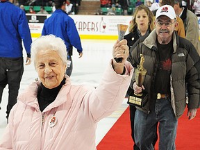 Evelyn Doucette, ringing her cowbell, and husband Sonny Doucette, carrying the Hounslow Memorial Award trophy, are followed by last year's winner, Lisa Leger, after an on-ice presentation Wednesday night at Yardmen Arena (Jason Miller/The Intelligencer)