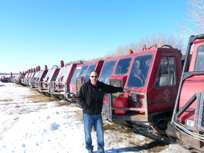 Lyle Bask with the lineup of tracked drilling machines his company uses for low impact seismic work. Some of the crawlers are equipped to carry water used during the drilling process but most have drills mounted.