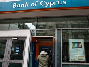 A man withdraws money from an automatic teller machine at a branch of Bank of Cyprus, in Athens March 16, 2013.The euro zone struck a deal on Saturday to hand Cyprus a bailout worth 10 billion euros, but demanded depositors in its banks forfeit some money to stave off bankruptcy despite the risks of a wider run on savings. In a radical departure from previous aid packages - and one that gave rise to incredulity and anger across the country - euro zone finance ministers forced Cyprus' savers to pay up to 10 percent of their deposits to raise almost 6 billion euros. REUTERS/Yannis Behrakis