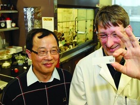 Dr. Guojun Liu and his partner John Dupont, a post-doctoral researcher, check out one of the slides used to examine the effects of their coating substance.     Rob Mooy-Kingston This Week
