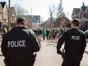 Kingston Police officers watch partygoers on Aberdeen Street during the early afternoon on Sunday. More than 1,000 people took to the streets around Aberdeen and William streets on Sunday, many clad in green in honour of St. Patrick’s Day. Police kept a distance, but were on hand to ensure things didn’t get out of hand. (Eric Healey For The Whig-Standard)