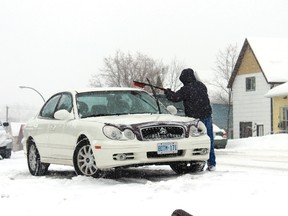 Harold King cleans snow off his car during the late winter storm Monday, March 18.