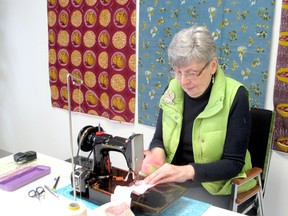 Annette Angood, a member of the Chatham-Kent Quilters' Guild, sews quilting strips. Fabric from Ghana hangs behind her. Wednesday March 20, 2013, Chatham, Ont.  (CARESSE LEY SPECIAL TO THE CHATHAM DAILY NEWS/ QMI AGENCY)
