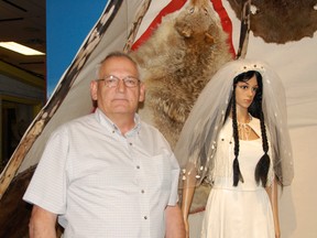 Collections and exhibit co-ordinator Garry Thate poses next to a traditional 1980 white-hide Cree wedding dress in the Grande Prairie Museum’s new exhibit, “The Wedding Dream.” (Elizabeth McSheffrey/Daily Herald-Tribune)