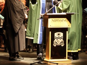 Colin Dennis, left, chairman of the Nipissing University Board of Governors, and Chancellor Jon S. Dellandrea, right, assist new Nipissing University President Mike DeGagne with his new robes, Friday, March 22, 2013, at the Capitol Centre. DeGagne was installed as the seventh president of Nipissing University and is the first aboriginal president of a university with its own charter in Canada.