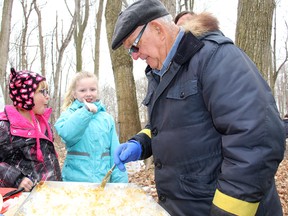 The first-ever Shrewsbury Maple Syrup Festival had an excellent turnout on Saturday. Here, Mia Wright, 8, centre, and Sawyer North, 6, enjoy some maple syrup taffy from volunteer Murray Knott in Sinclair's Bush. TREVOR TERFLOTH trevor.terfloth@sunmedia.ca