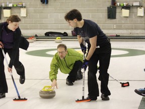 Skip Tim Phillips, from Sudbury Curling Club, throws a rock while Gillian Gerfelz and David Daoust prepare to sweep.