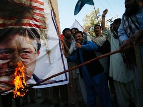 Supporters of Awami Majlis-e-Amal Pakistan (AMAP) burn an image of Pakistan's former President Pervez Musharraf and the U.S flag during a protest in Quetta March 24, 2013. REUTERS/Naseer Ahmed