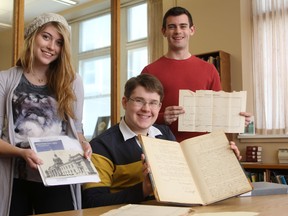Second-year history students Kirsten Andersen, left, Daniel Rose and Blake Butler hold archived police records from the late 1880s and early 1900s. The documents, housed at the Queen’s University Archives, shed light on the daily lives of police and citizens in Kingston. (Danielle VandenBrink The Whig-Standard)