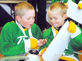 Two Timbit Green players check out their medals and Sidney Crosby activity boards, courtesy of Tim Hortons, following their Stratford Rotary Hockey tyke division game at the Allman Arena Sunday.
