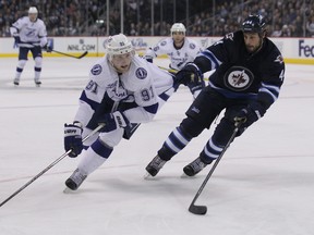 Winnipeg Jets defenceman Zach Bogosian (right) grabs the sweater of  Steven Stamkos of the Tampa Bay Lightning during the third period at MTS Centre in Winnipeg on Sun., March 24, 2013.